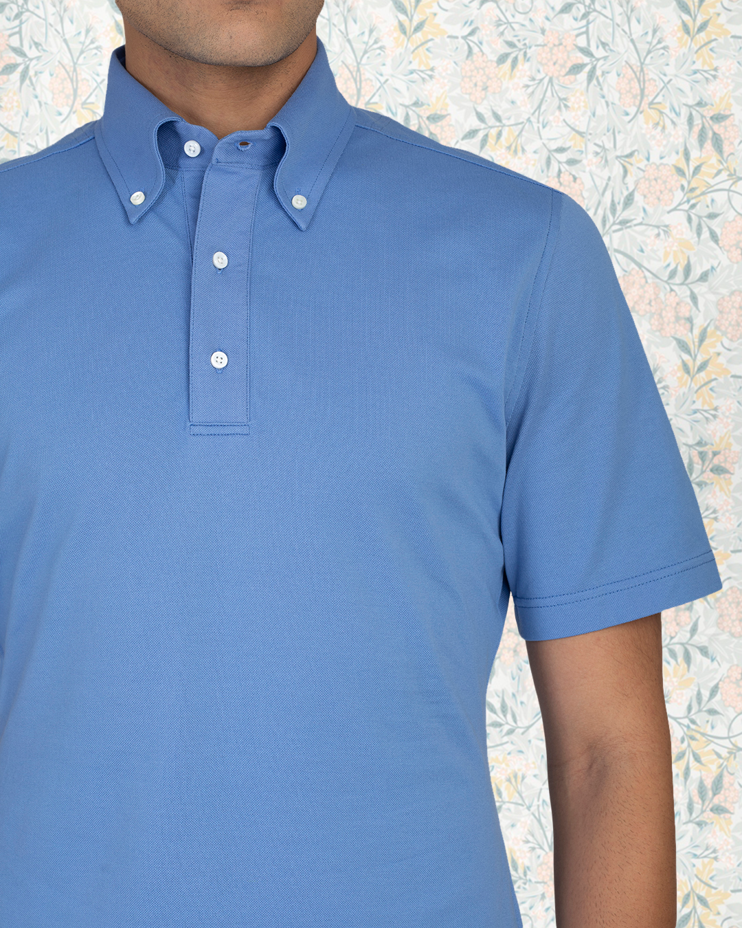 Close up view of model wearing the custom oxford polo shirt for men by Luxire in soft blue