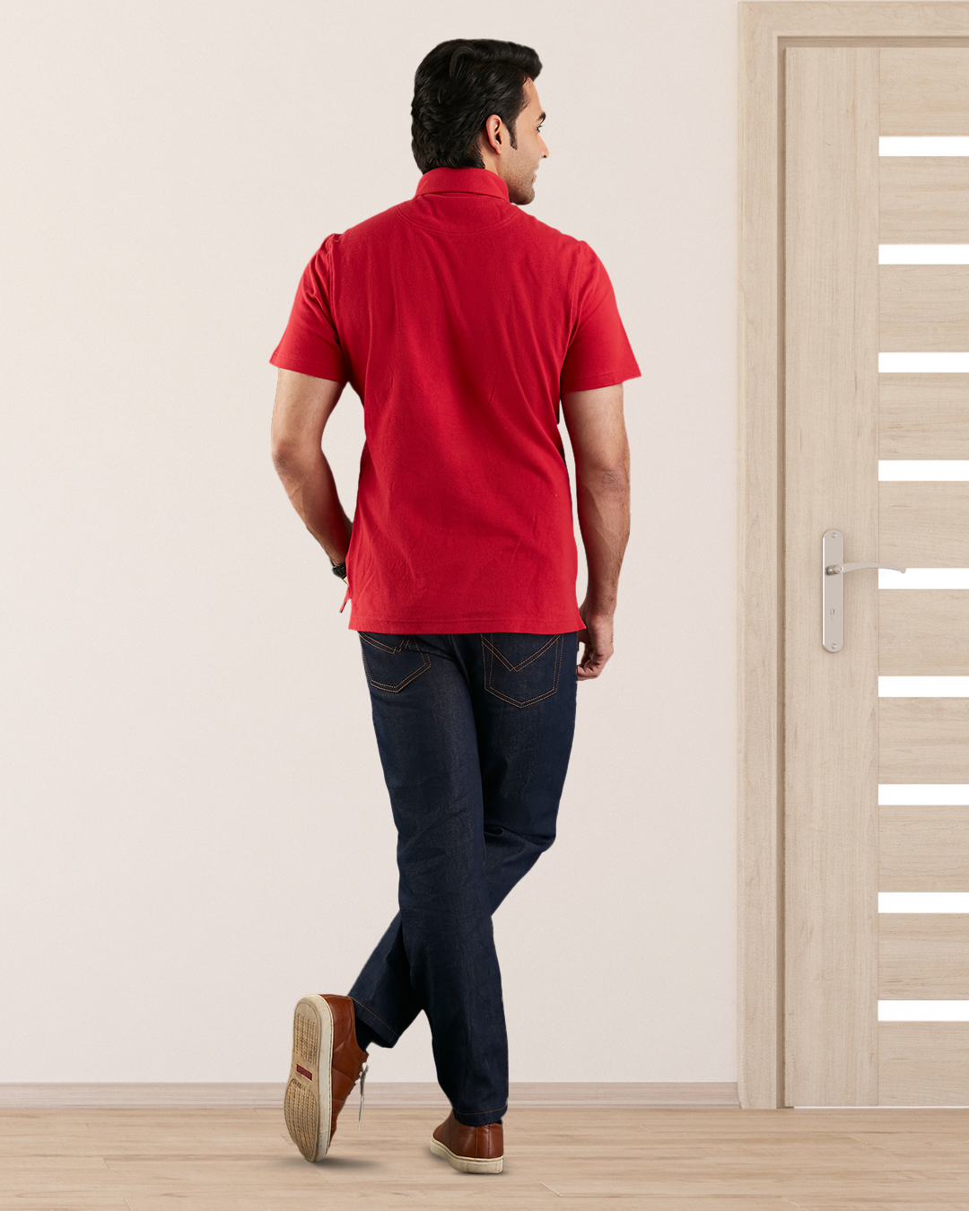 Back of model wearing the custom oxford polo shirt for men by Luxire in red hands at side