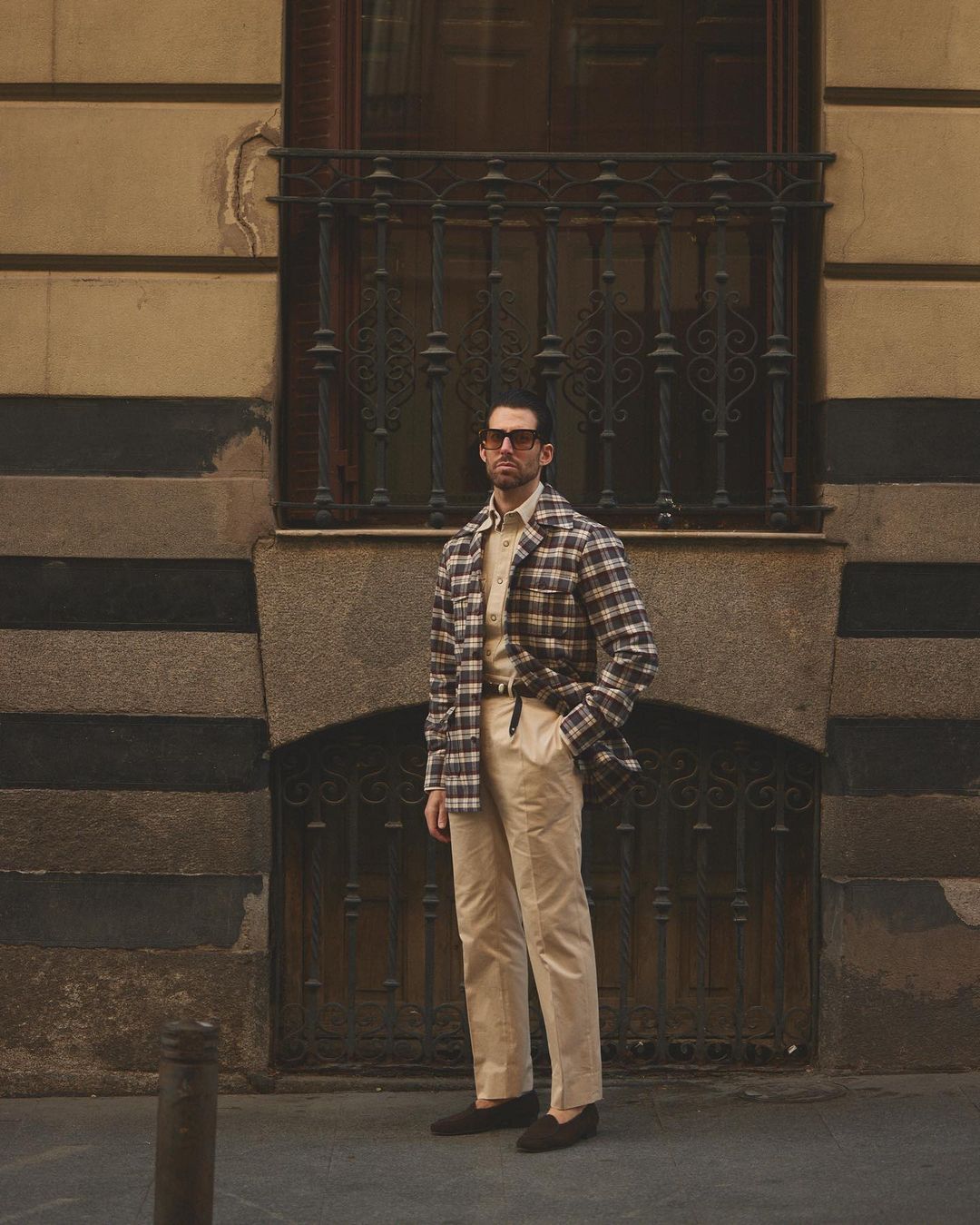 Front of model wearing the flannel shirt jacket for men by Luxire in brown and ecru checks in fron tof building