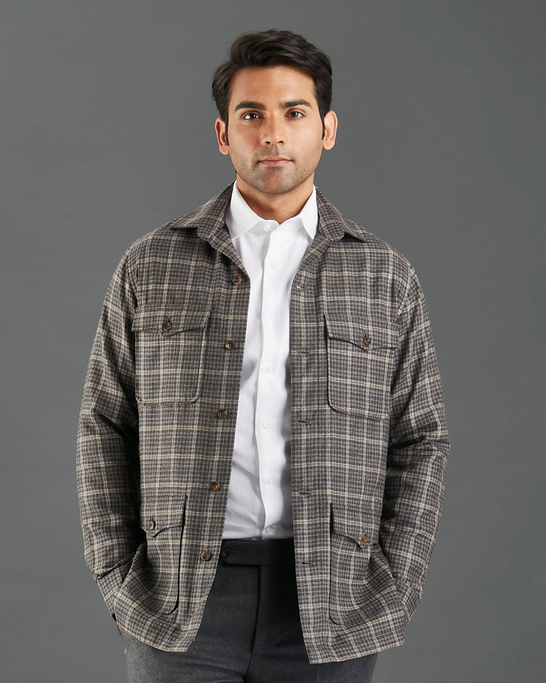 Front of model wearing the shirt jacket for men by Luxire in brown and grey overchecks hands in pockets