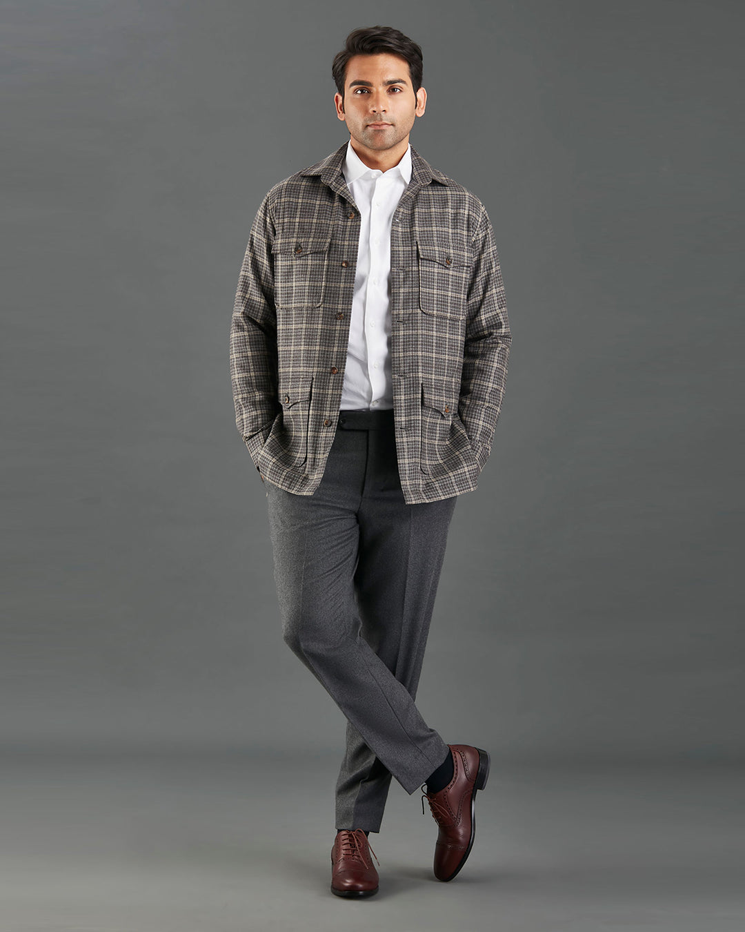 Front of model wearing the shirt jacket for men by Luxire in brown and grey overchecks hands in pockets