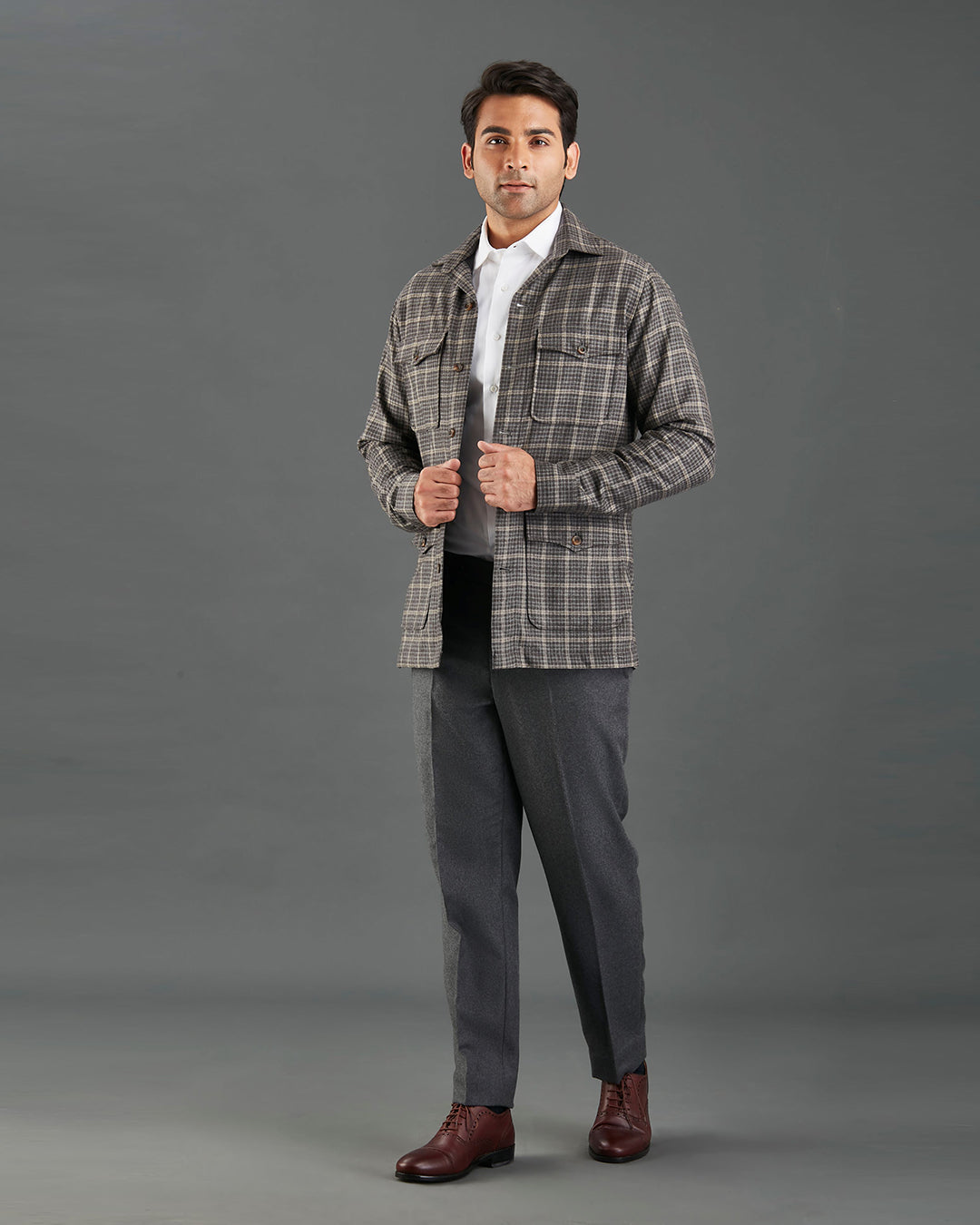 Front of model wearing the shirt jacket for men by Luxire in brown and grey overchecks hands together