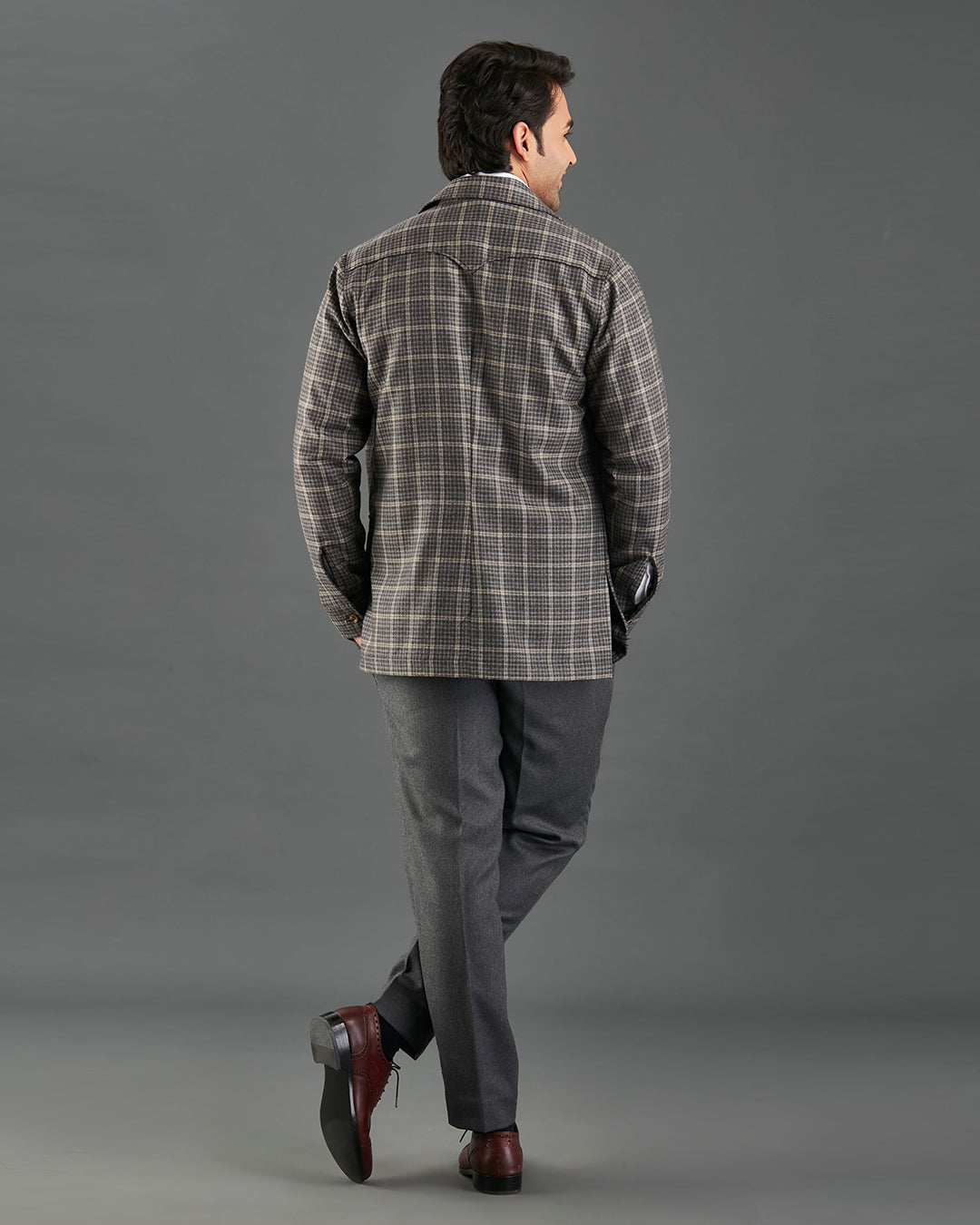 Back of model wearing the shirt jacket for men by Luxire in brown and grey overchecks