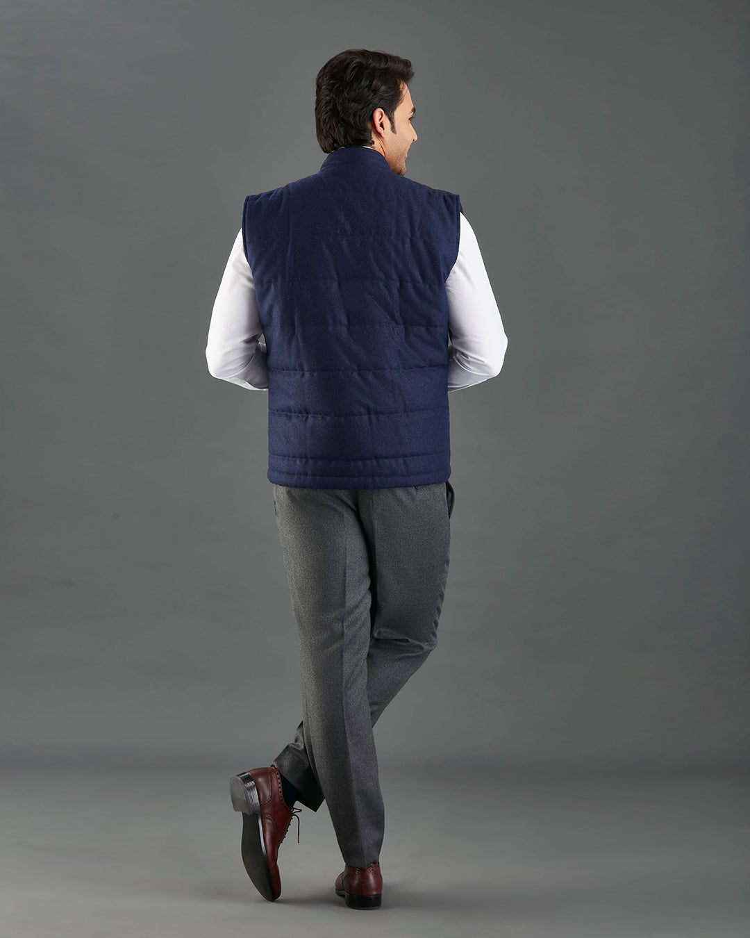 Back of model wearing the flannel quilted vest for men by Luxire in navy hands in pockets