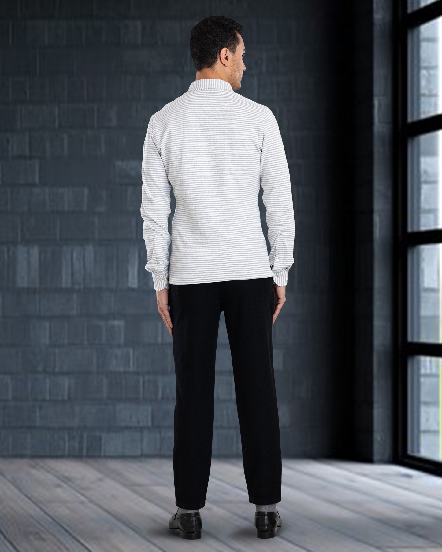 Back of model wearing custom wool Chino pants for men by Luxire in black next to window