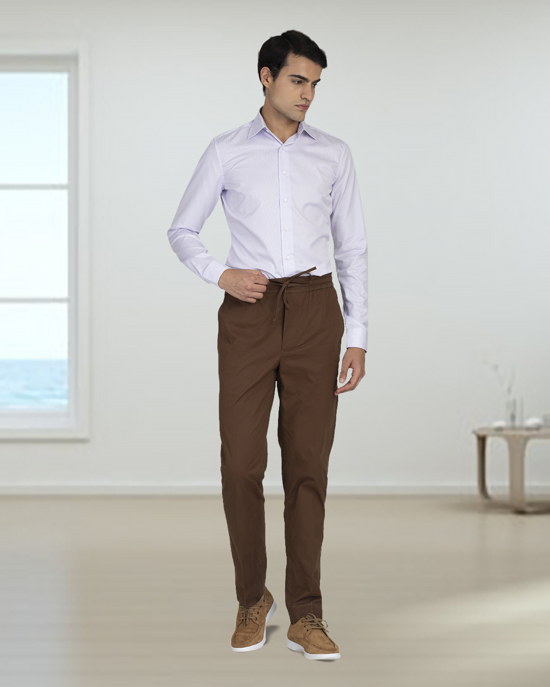 Model wearing custom Genoa drawstring pants for men by Luxire in coffee brown one hand at waist