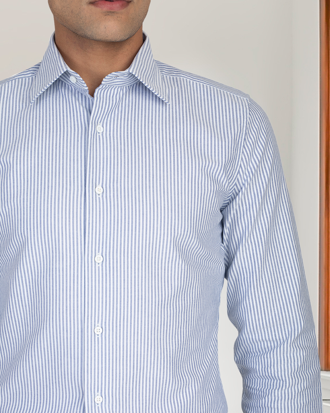 Close up of model wearing the custom oxford shirt for men by Luxire in white with navy stripes