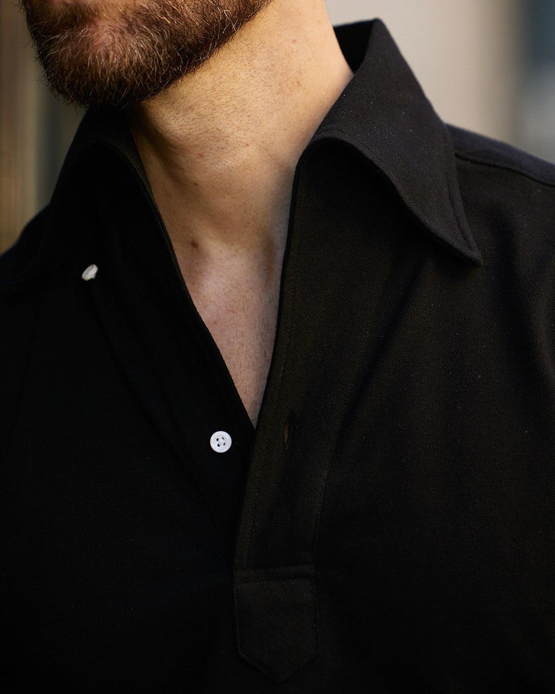 Close up of model wearing the custom oxford polo shirt for men by Luxire in black pique
