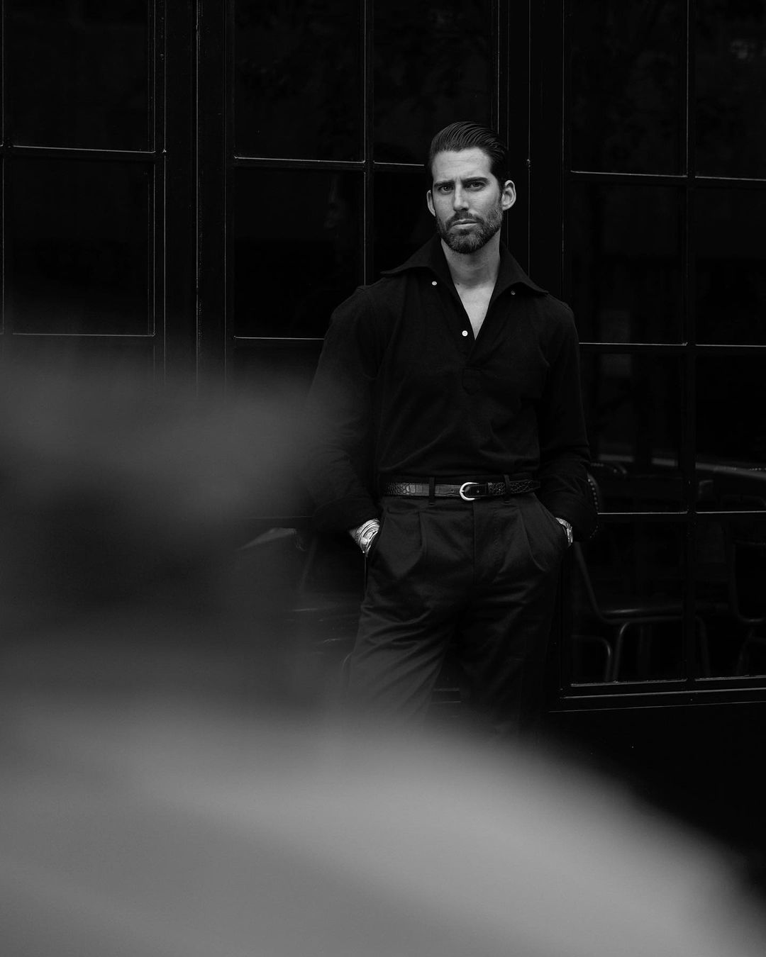 Distant model wearing the custom oxford polo shirt for men by Luxire in black pique hands in pockets