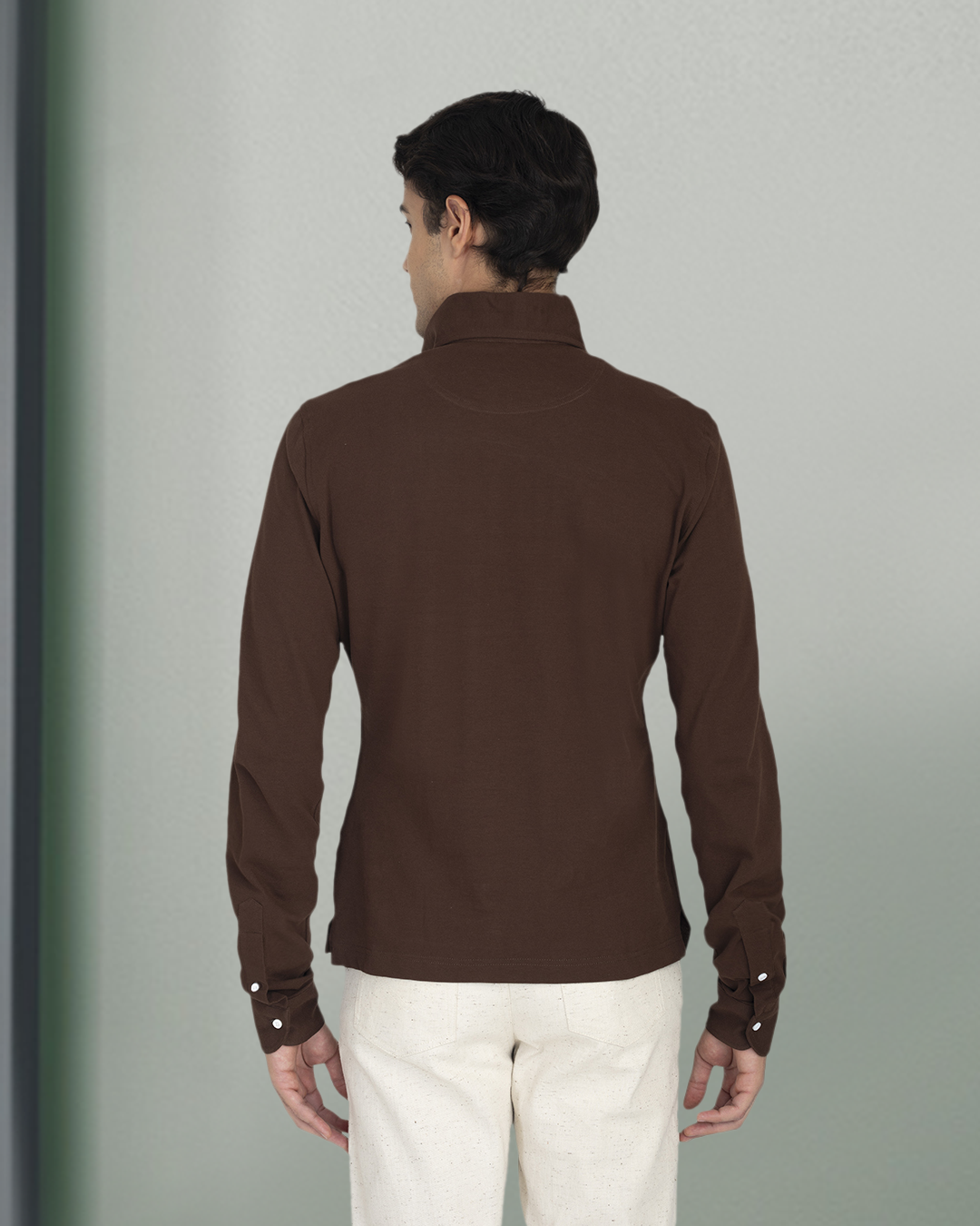 Back of model wearing the custom oxford polo shirt for men by Luxire in brown pique hands at side