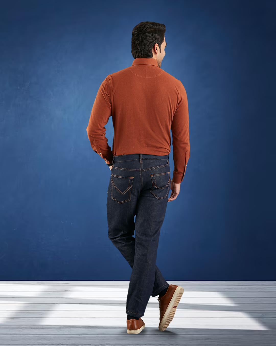 Back of model wearing the custom oxford polo shirt for men by Luxire in copper hand at side