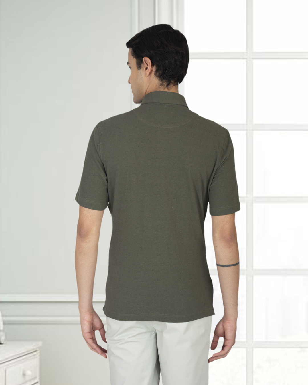 Back of model wearing the custom oxford polo shirt for men by Luxire in olive green hands at side 2
