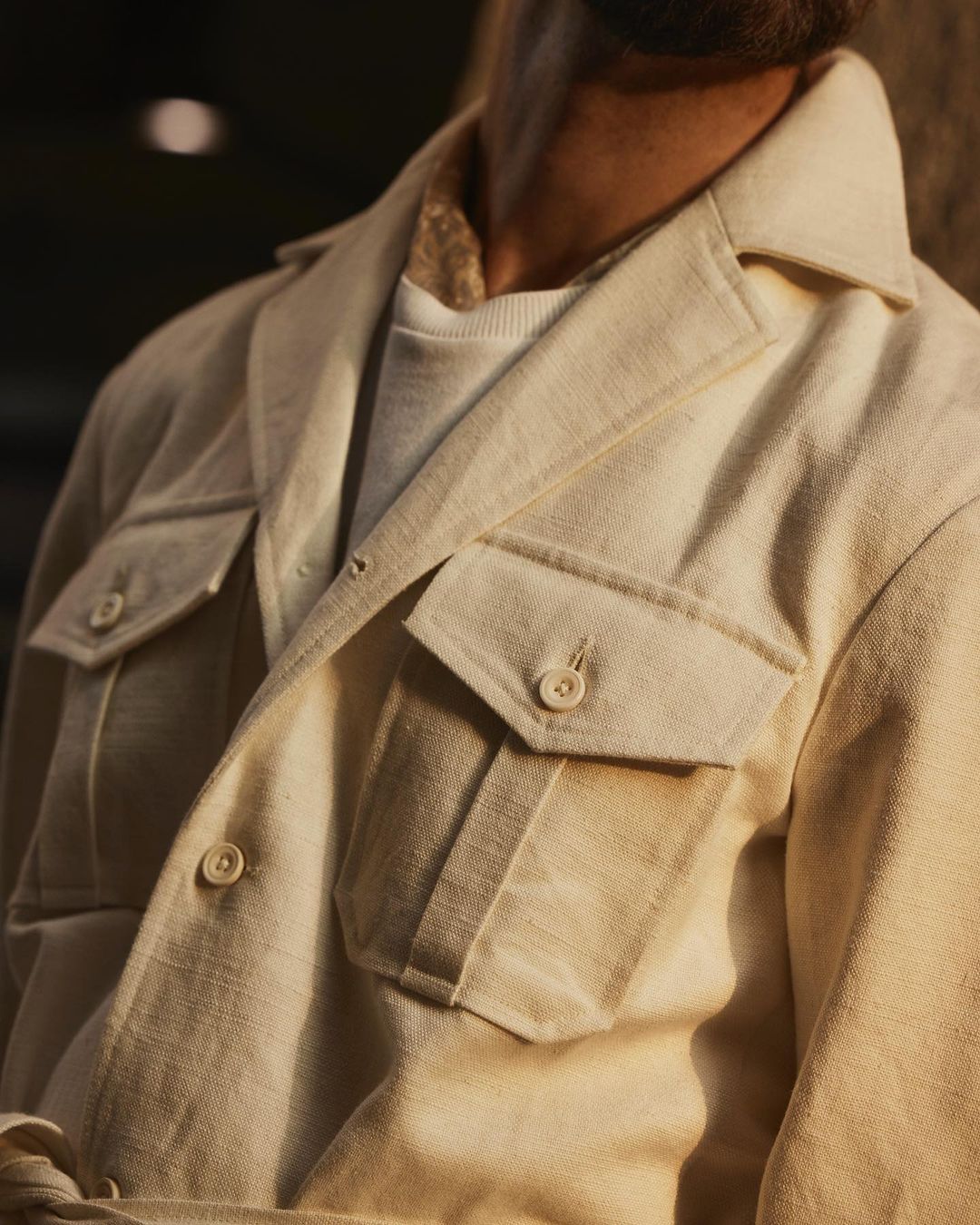 Close up of model outside wearing the safari jacket in linen cotton for men by Luxire in off white 2
