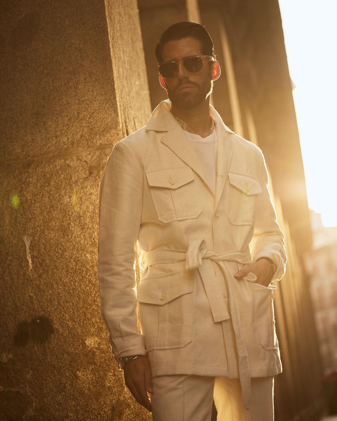 Model outside wearing the safari jacket in linen cotton for men by Luxire in off white sun in the background