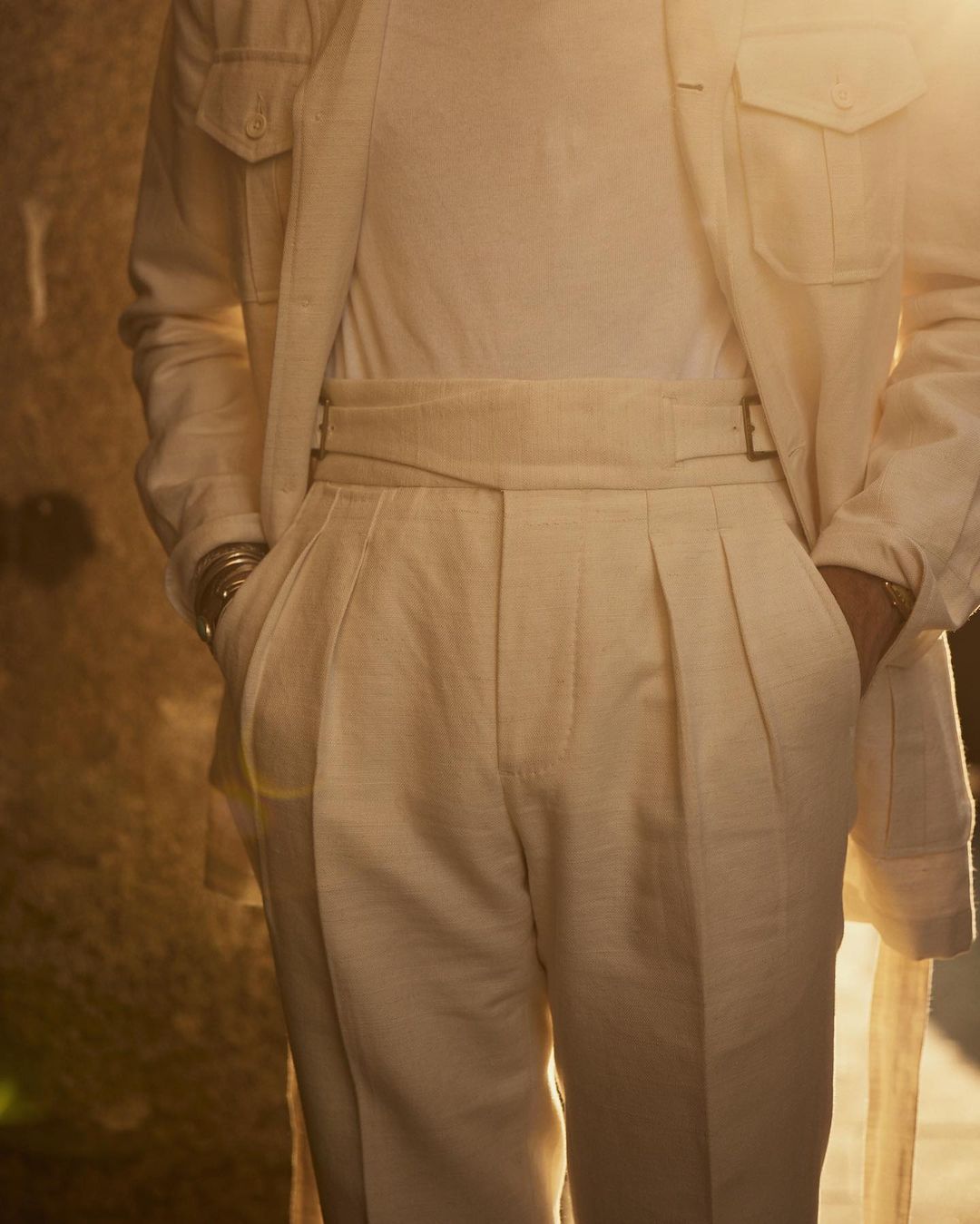 Close up of model outside wearing the safari jacket in linen cotton for men by Luxire in off white hands in pockets